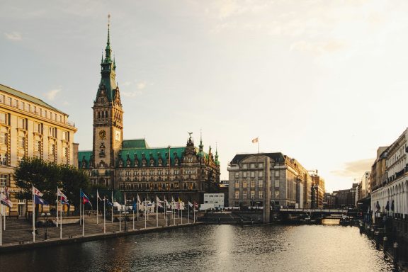 Historisches Hamburger Rathaus und Kanal bei Sonnenuntergang.