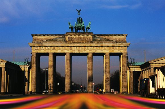 Das Brandenburger Tor bei Sonnenuntergang, mit bunten Lichtern im Vordergrund.