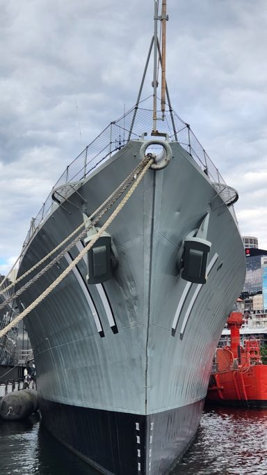 Ein graues Schiff mit auffälligen Bugdetails im Hafen.