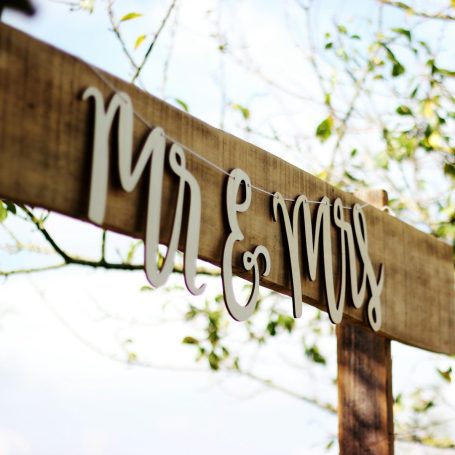 Holzschild mit der Aufschrift "Mr & Mrs" vor einem unscharfen Hintergrund.