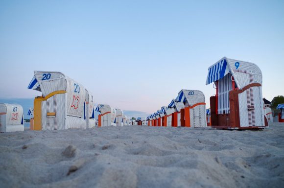 Reihen von bunten Strandkörben auf einem Sandstrand bei Dämmerung.