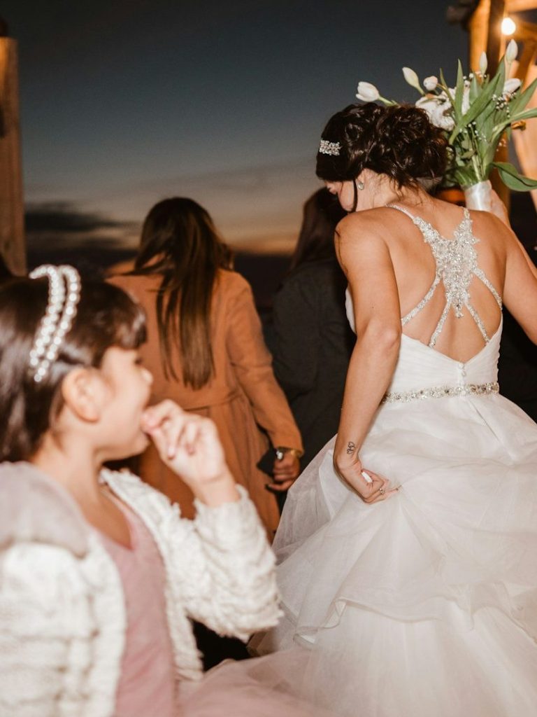 Eine Braut in einem eleganten Kleid, während ein Mädchen sie neugierig beobachtet.