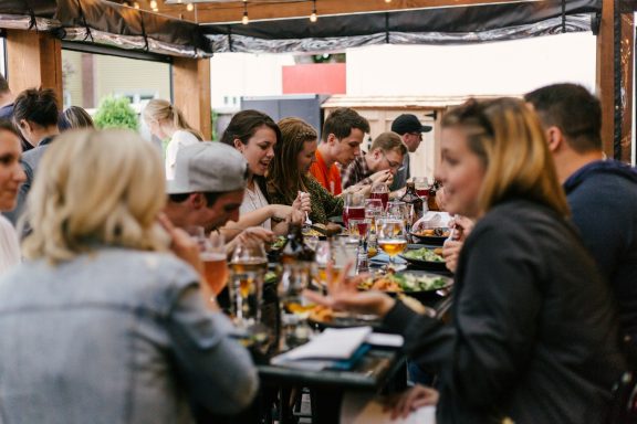 Vielbelebte Restaurantterrasse mit Gästen, die Speisen und Getränke genießen.